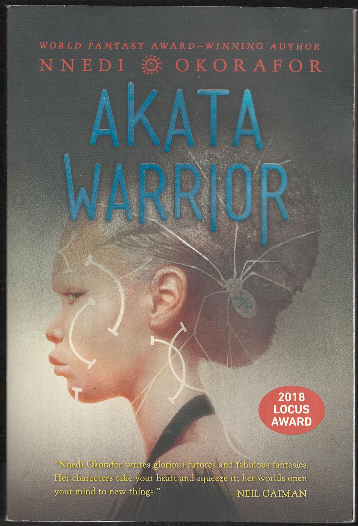 Front cover of Akata Warrior by Nnedi Okorafor, featuring a side profile of a young woman with white line drawings overlaid on the face and hair.