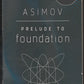 Front cover of Prelude to Foundation by Isaac Asimov with a stylized atom symbol on a dark background.